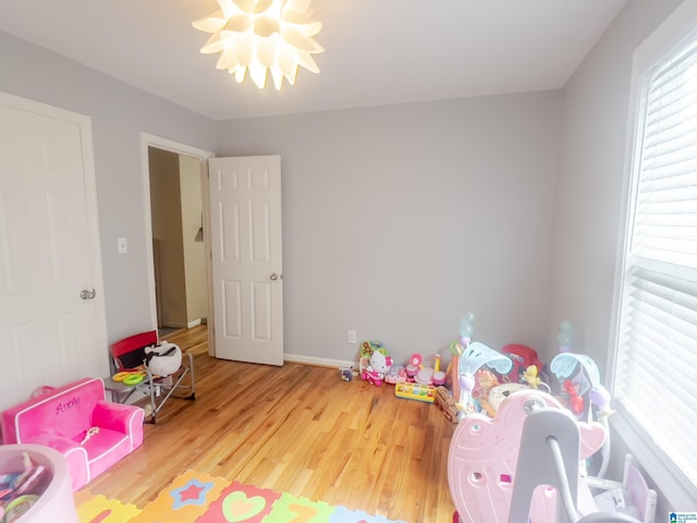 rec room featuring wood finished floors, a notable chandelier, and baseboards