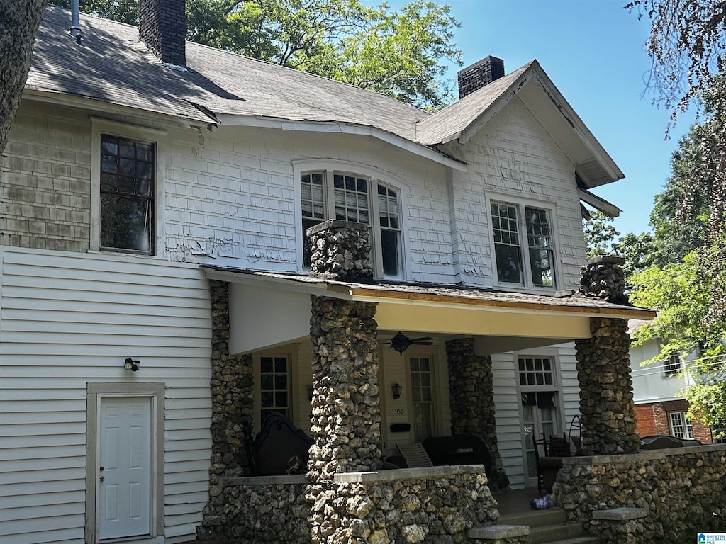 rear view of house featuring a porch, a chimney, and a ceiling fan