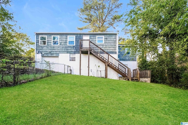 back of property featuring a yard, an attached garage, fence, and stairs