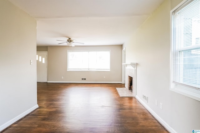 unfurnished living room featuring a fireplace with flush hearth, wood finished floors, ceiling fan, and baseboards