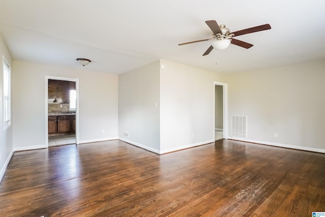 unfurnished room with dark wood-style flooring, baseboards, a ceiling fan, and visible vents