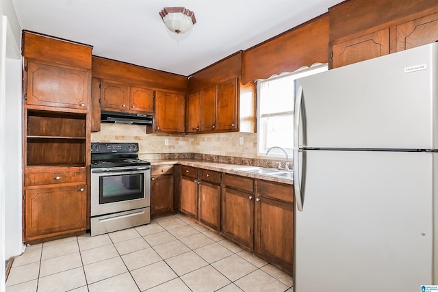 kitchen with freestanding refrigerator, stainless steel range with electric stovetop, under cabinet range hood, a sink, and backsplash