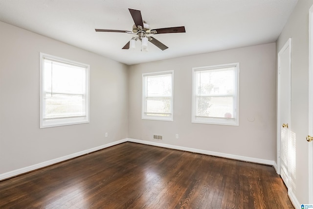 spare room with dark wood-style floors, baseboards, visible vents, and ceiling fan
