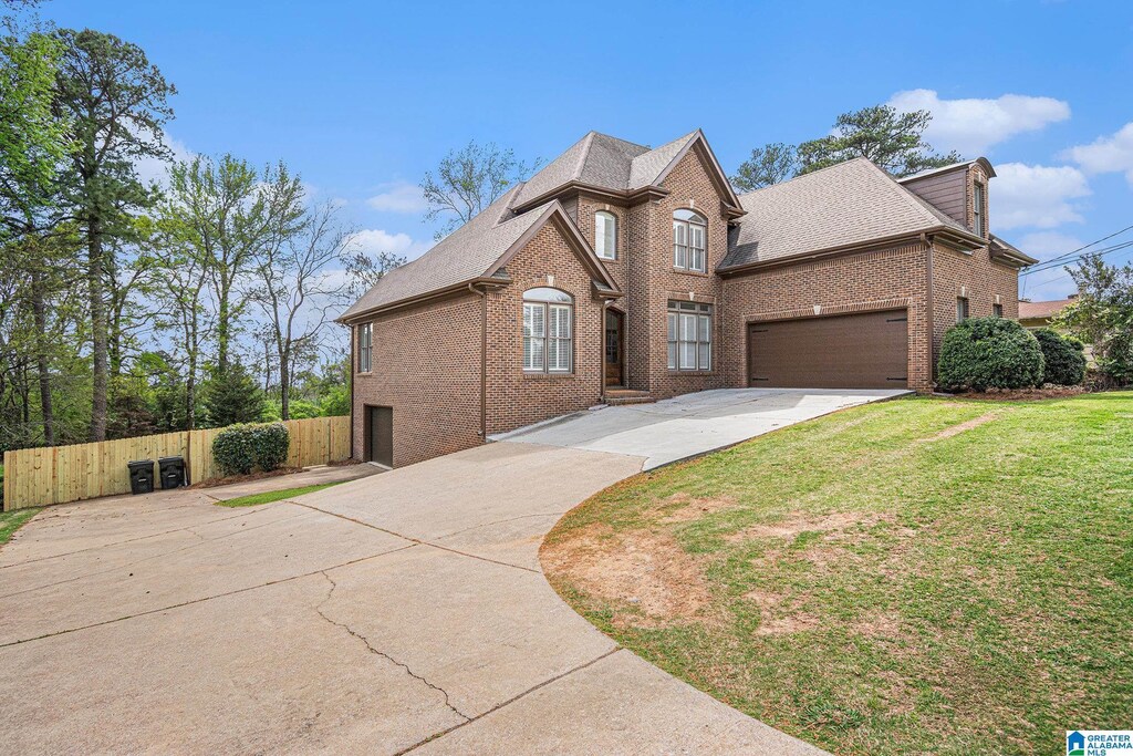 2208 Jacobs Rd, Vestavia Hills, AL 35216 - traditional-style home featuring a front yard, a shingled roof, fence, concrete driveway, and brick siding
