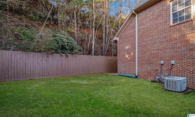 view of yard with a fenced backyard and central AC unit