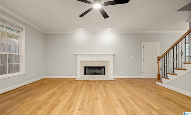 unfurnished living room featuring stairs, light wood-style flooring, a ceiling fan, and ornamental molding