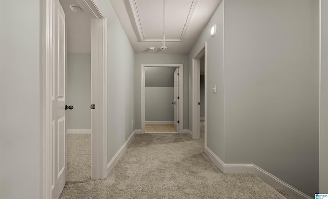 corridor with attic access, baseboards, and carpet floors