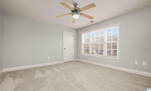 spare room featuring light carpet, ceiling fan, baseboards, and visible vents