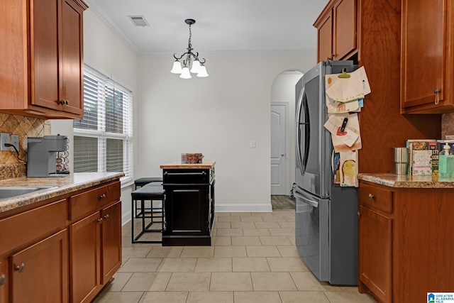 kitchen with an inviting chandelier, visible vents, arched walkways, freestanding refrigerator, and decorative backsplash