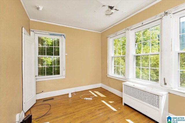 2701 21st St, Birmingham, AL 35208 - spare room featuring baseboards, crown molding, radiator heating unit, visible vents, and wood finished floors