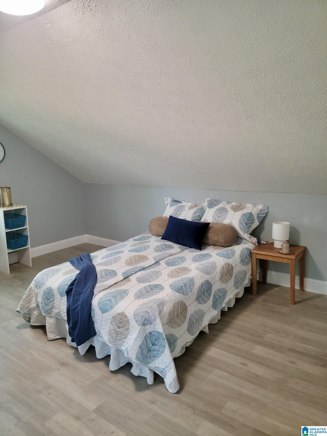627 Sidney Cir, Anniston, AL 36207 - bedroom featuring vaulted ceiling, wood finished floors, a textured ceiling, and baseboards