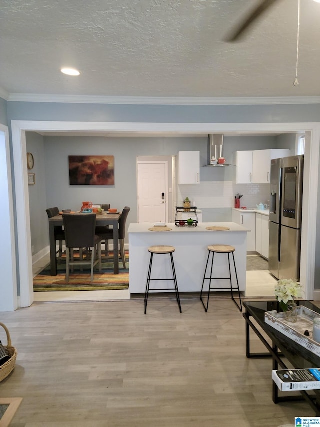 627 Sidney Cir, Anniston, AL 36207 - kitchen featuring wall chimney range hood, stainless steel refrigerator with ice dispenser, crown molding, and white cabinets