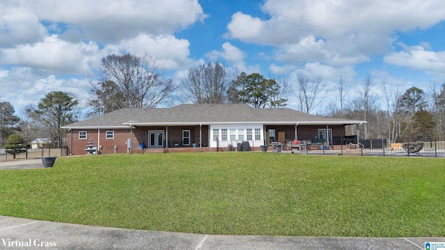 rear view of property with a yard, fence, and brick siding