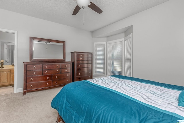 carpeted bedroom with baseboards, ensuite bath, a textured ceiling, and a ceiling fan