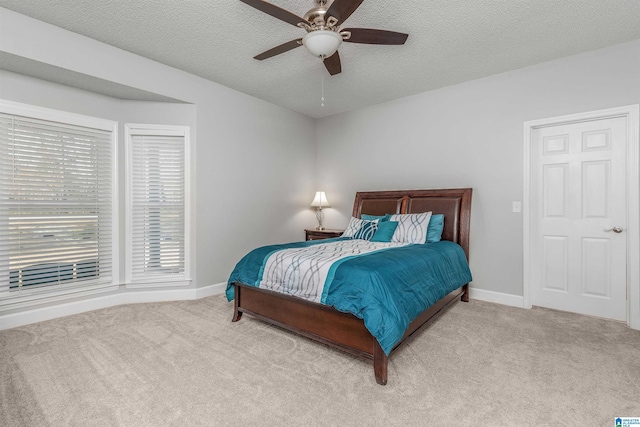 carpeted bedroom with a textured ceiling, baseboards, and a ceiling fan
