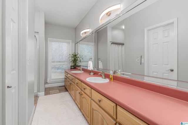 bathroom featuring a sink, baseboards, and double vanity