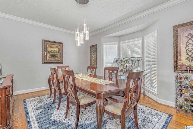 dining room featuring crown molding, light wood finished floors, a chandelier, and a healthy amount of sunlight