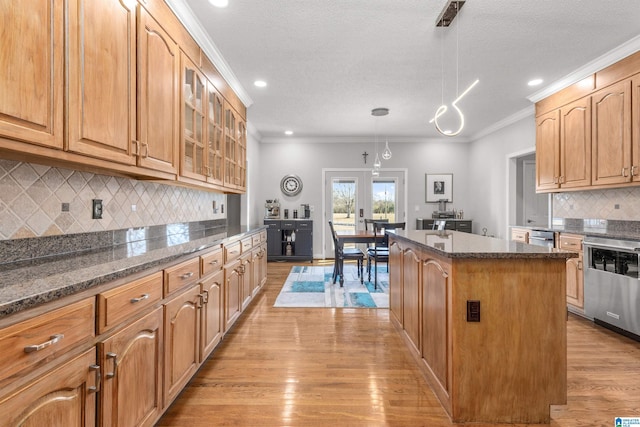 kitchen featuring glass insert cabinets, a center island, crown molding, light wood-style floors, and stainless steel dishwasher