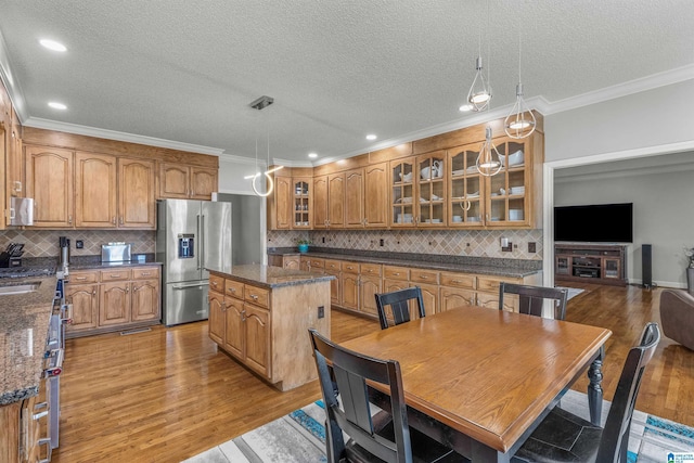 kitchen featuring brown cabinetry, a center island, high end fridge, and light wood-style floors
