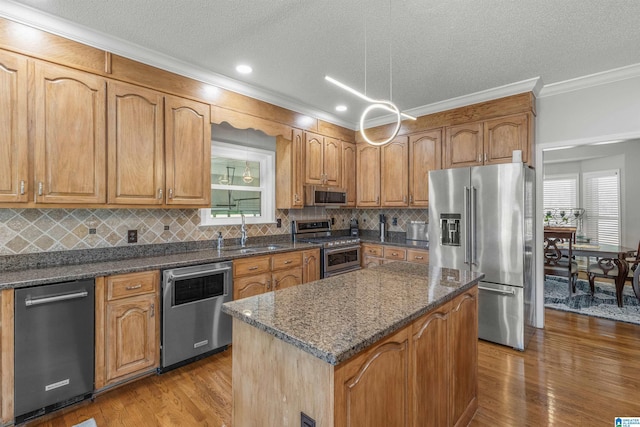 kitchen featuring tasteful backsplash, a sink, appliances with stainless steel finishes, crown molding, and wood finished floors