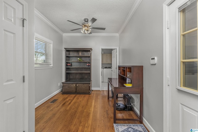 interior space with ornamental molding, ceiling fan, a textured ceiling, wood finished floors, and washer and clothes dryer