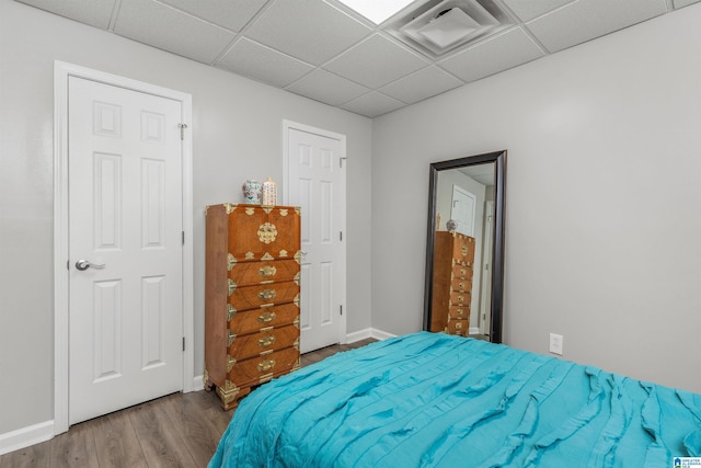 bedroom featuring visible vents, baseboards, a paneled ceiling, and wood finished floors