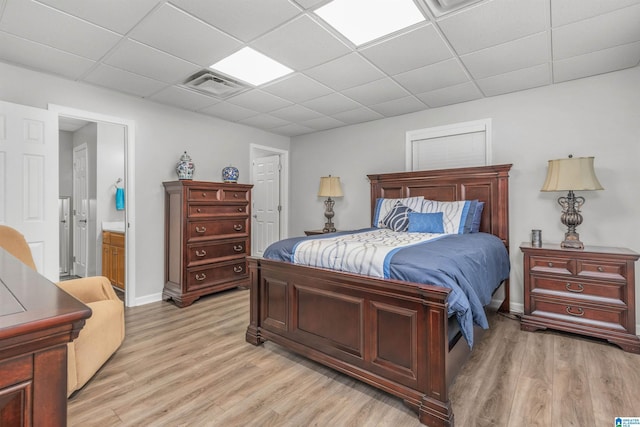 bedroom featuring visible vents, a drop ceiling, baseboards, and light wood-style flooring