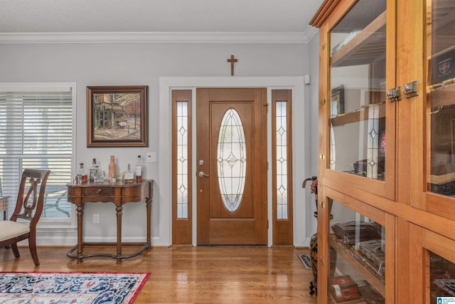 foyer entrance featuring visible vents, crown molding, and wood finished floors
