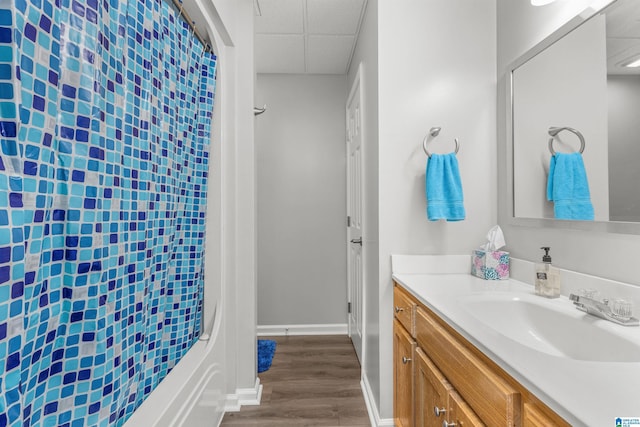 full bath featuring vanity, a paneled ceiling, baseboards, and wood finished floors
