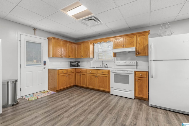 kitchen with white appliances, light countertops, under cabinet range hood, visible vents, and a sink