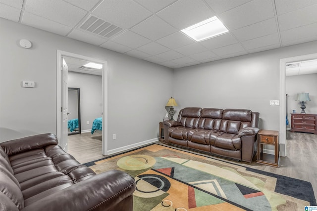 living room with a paneled ceiling, wood finished floors, baseboards, and visible vents