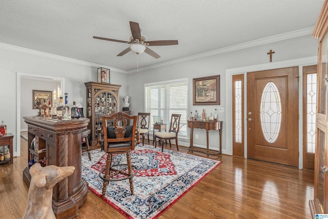 entrance foyer with crown molding, a textured ceiling, a ceiling fan, wood finished floors, and baseboards