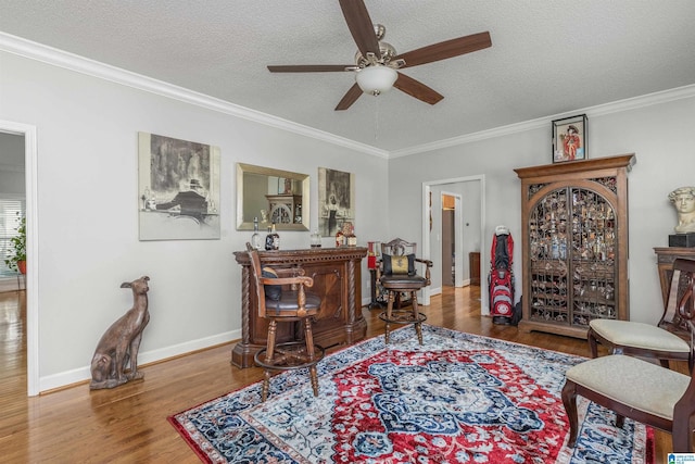 living room with ornamental molding, ceiling fan, wood finished floors, and a textured ceiling