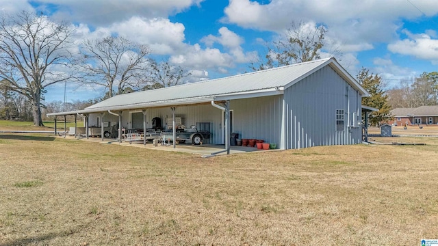 rear view of property with a carport, metal roof, and a lawn