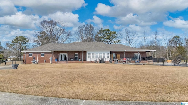 back of property with a lawn, fence, and brick siding