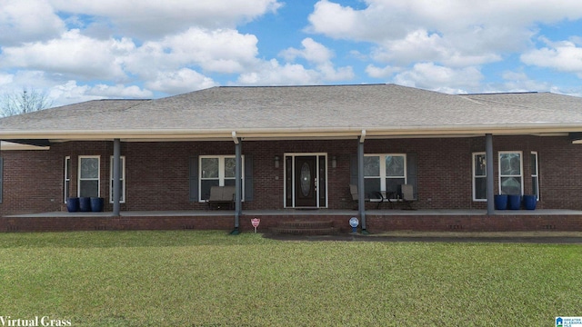 rear view of house featuring brick siding, a porch, and a lawn