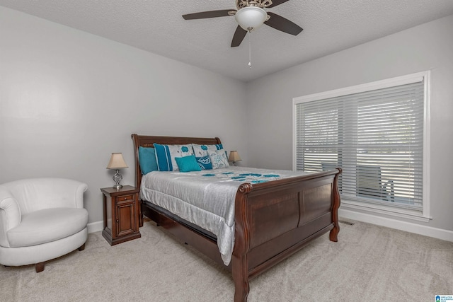 bedroom featuring a textured ceiling, light colored carpet, baseboards, and a ceiling fan