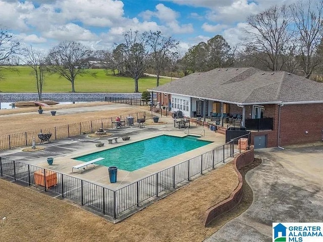 view of pool with a diving board, a patio area, a yard, fence, and a fenced in pool