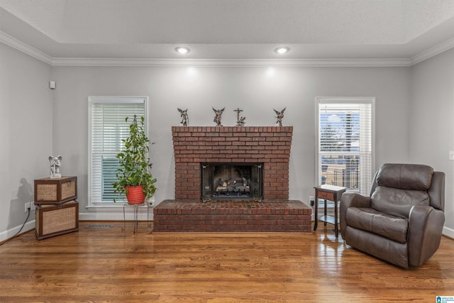 living room featuring a fireplace, visible vents, ornamental molding, and wood finished floors
