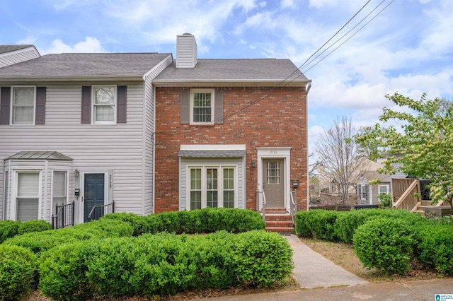 view of front of property with brick siding, a shingled roof, and a chimney