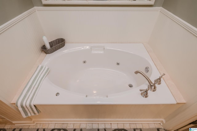 details with a tub with jets and a wainscoted wall
