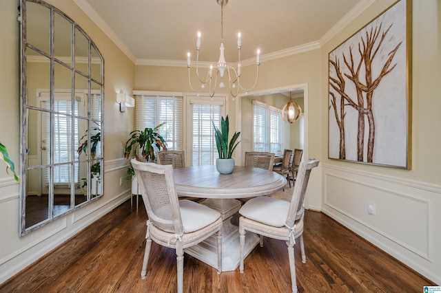 dining space with a decorative wall, an inviting chandelier, crown molding, and wood finished floors