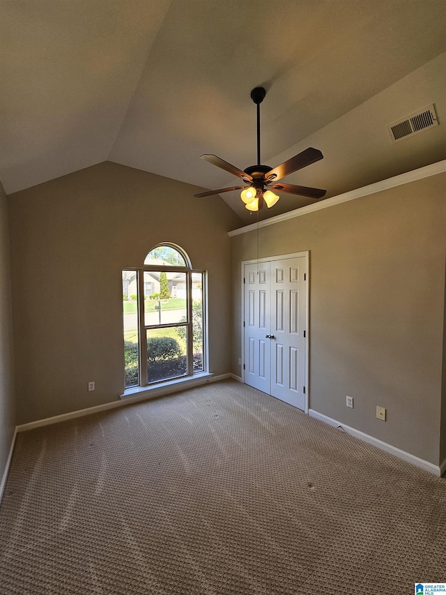 unfurnished bedroom with carpet, a closet, visible vents, lofted ceiling, and baseboards
