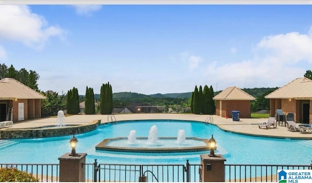 community pool with an outbuilding, a patio area, and fence