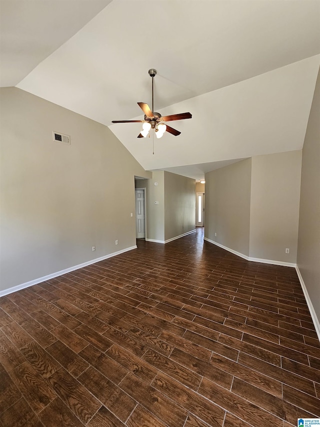 spare room featuring ceiling fan, visible vents, lofted ceiling, baseboards, and dark wood-style floors