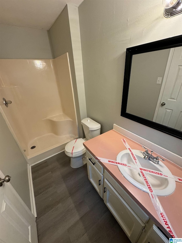 full bath featuring vanity, walk in shower, toilet, and wood finished floors