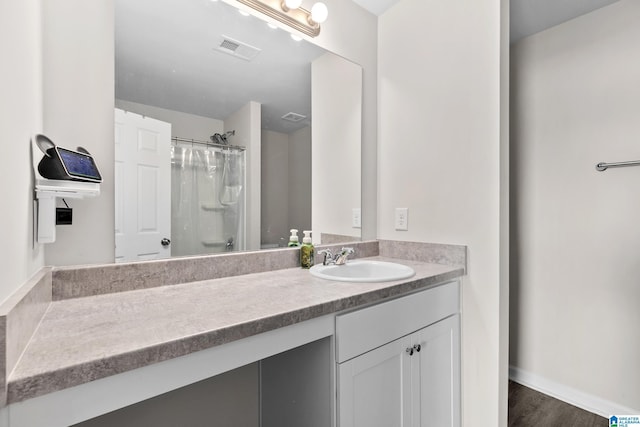 bathroom featuring wood finished floors, vanity, curtained shower, and visible vents