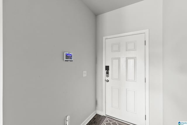 doorway with baseboards and dark wood-style floors