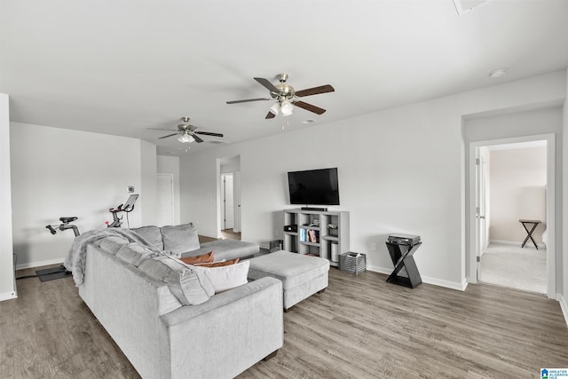 living room with baseboards, a ceiling fan, and light wood-style flooring