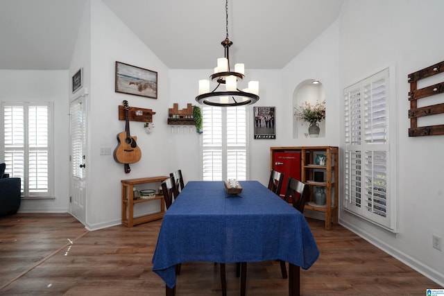 dining area featuring a chandelier, baseboards, wood finished floors, and lofted ceiling